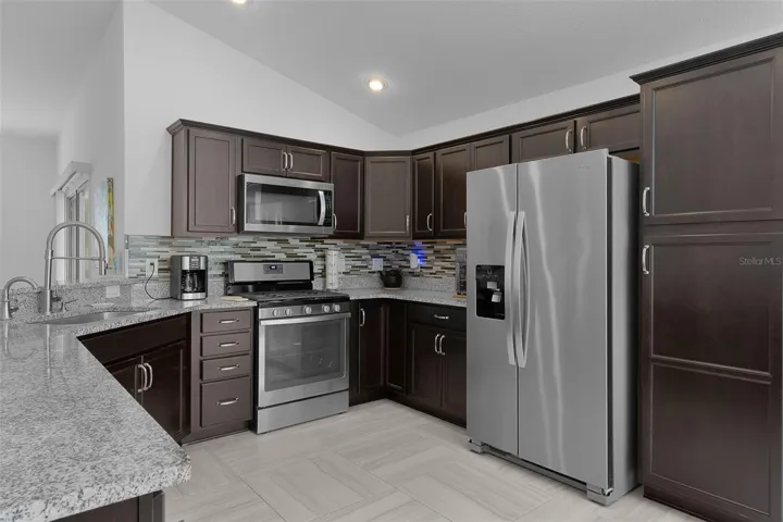 Stainless steel appliances, espresso color cabinets with hardware &amp; backsplash &amp; pantry cabinet