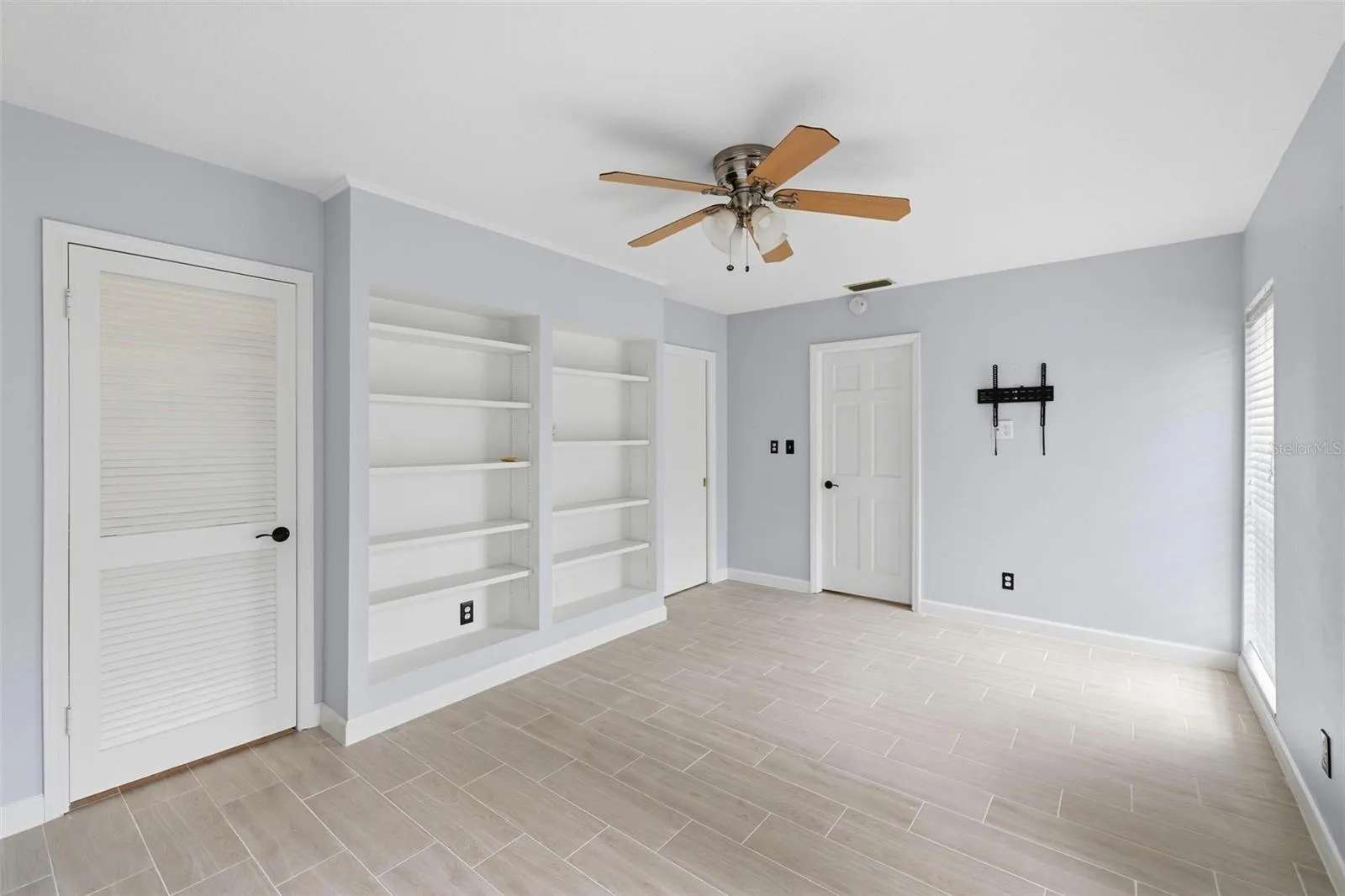 Full view of the built in shelves in the 2nd bedroom.  Door to closet and door to laundry room.