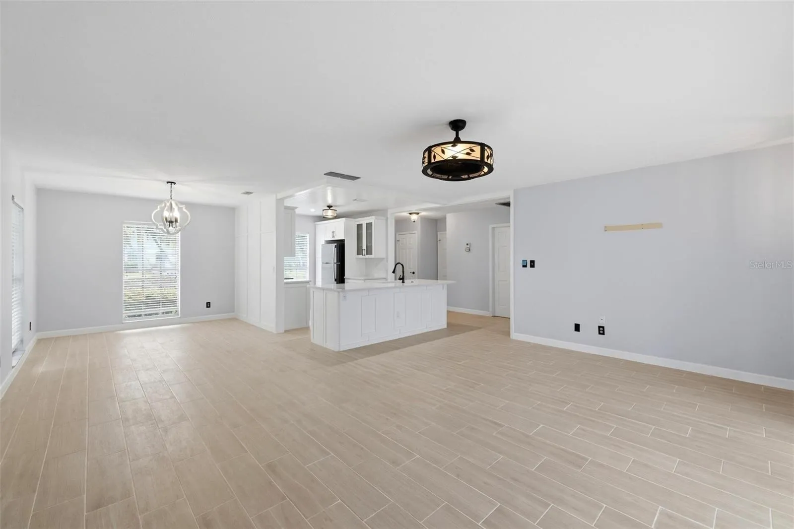 This view shows the open floorplan including living room, dining room and kitchen including a view of the newly laid tile floors throughout the home.