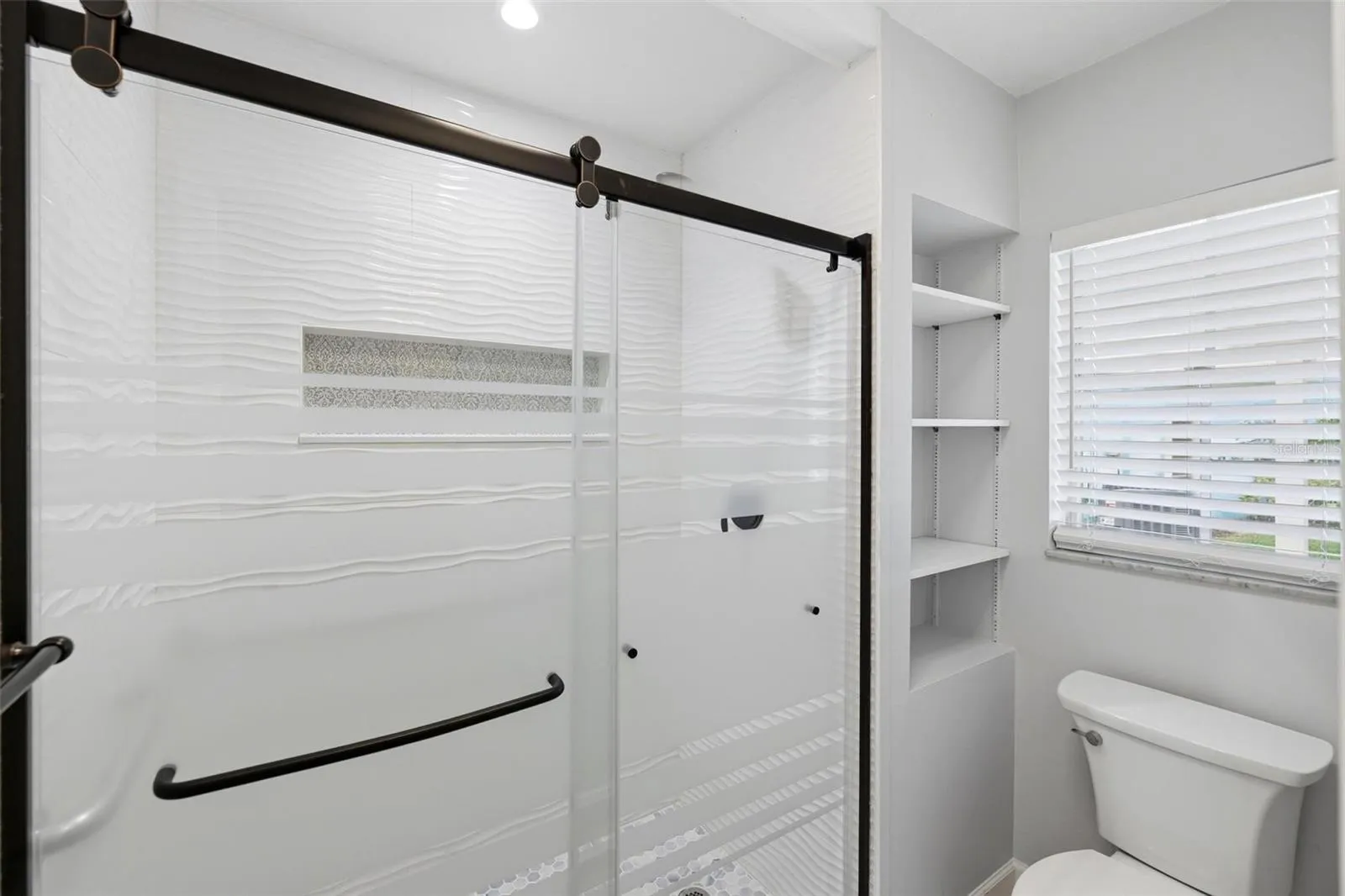 Another view of the primary bath shower and toilet area along with window for light and bright!