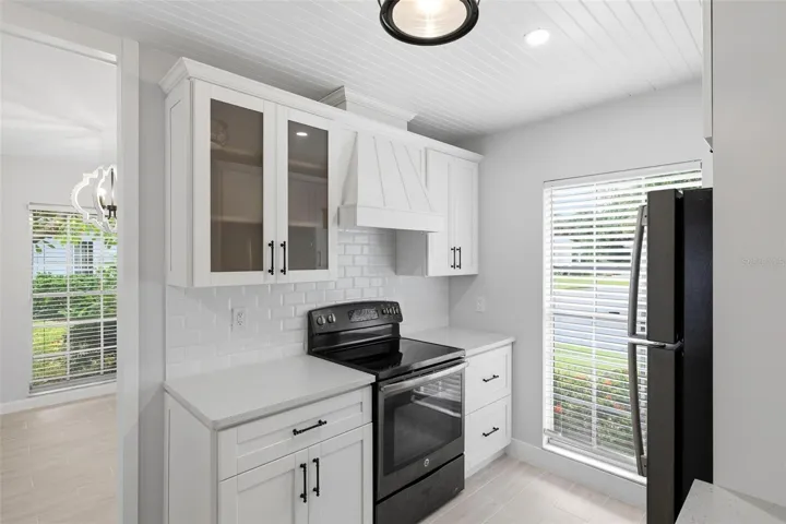Another view of the kitchen including the stove and cabinetry.  Glass door cabinet for your glassware or special dishes.