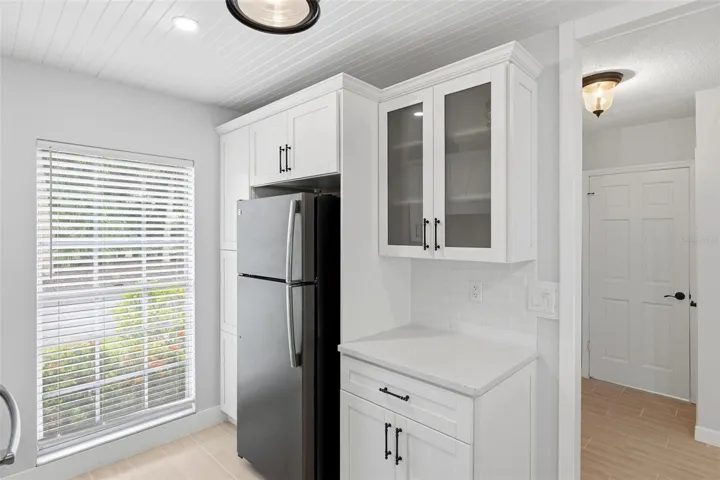 The opposite wall of the kitchen with pantry area, refrigerator and large window lending lots of natural light into the kitchen.