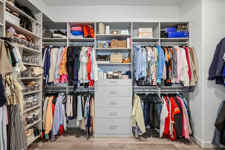 Primary bedroom closet with custom organizers built in