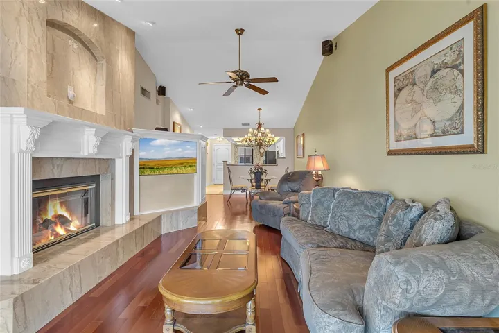 Spacious Living Room Featuring Vaulted Ceilings, Wood Flooring, Custom Built-Ins, and a Beautiful Fireplace