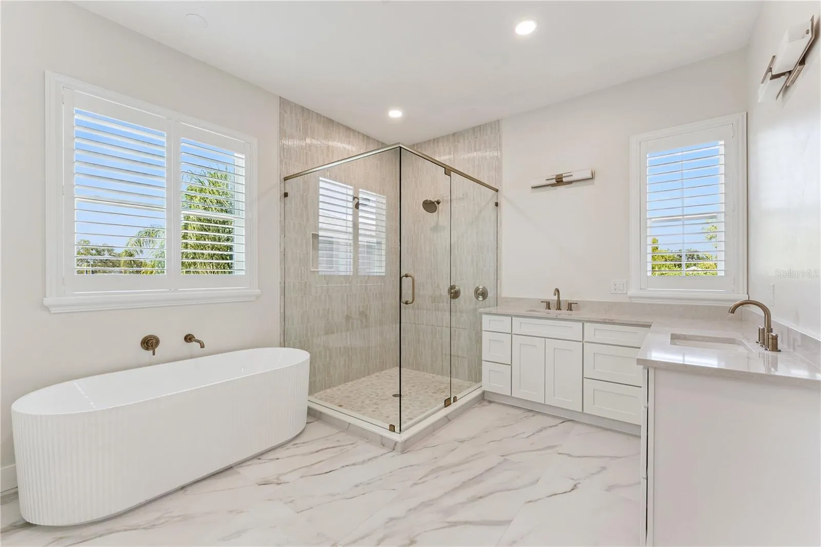A freestanding tub, glass-enclosed shower, and two sinks define this spacious bathroom.