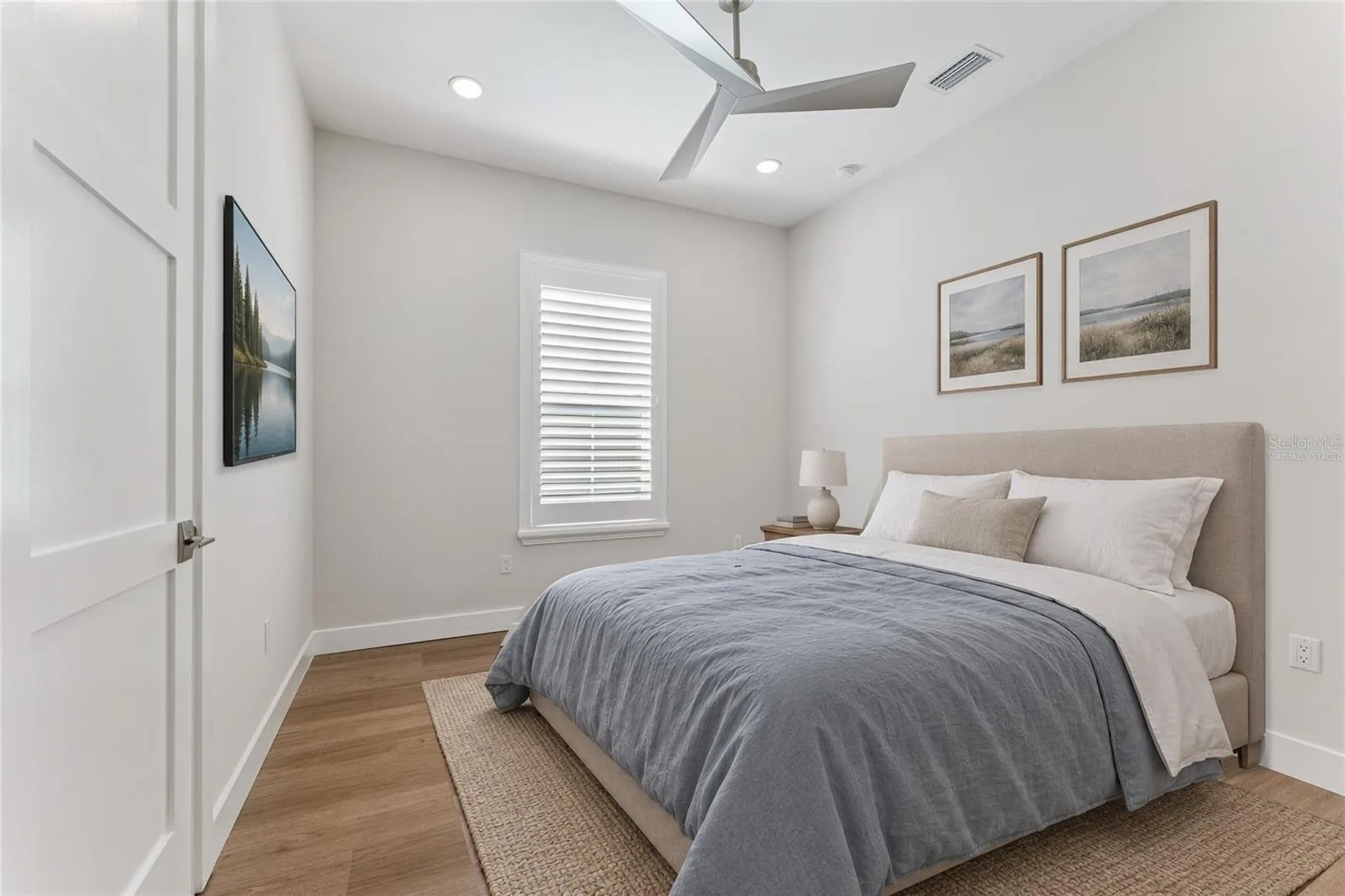 Virtually Staged - This bedroom features a white ceiling fan, shuttered window, and light finishes.