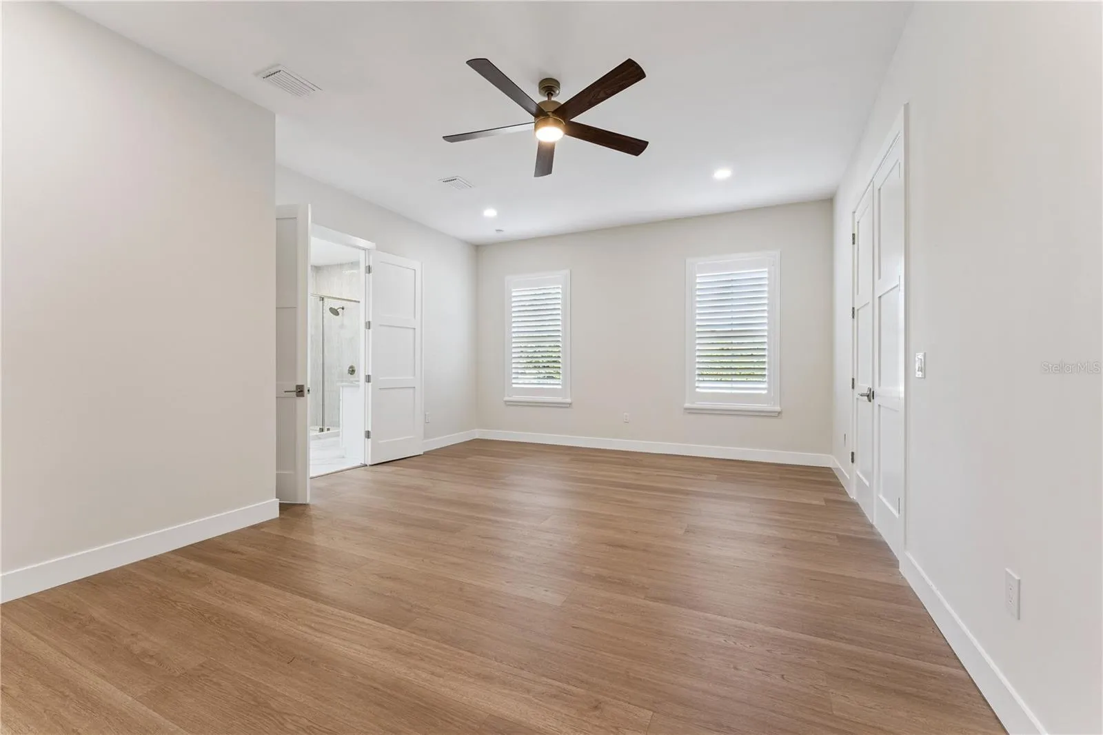 A second view of the primary bedroom shows its windows and open floor space.