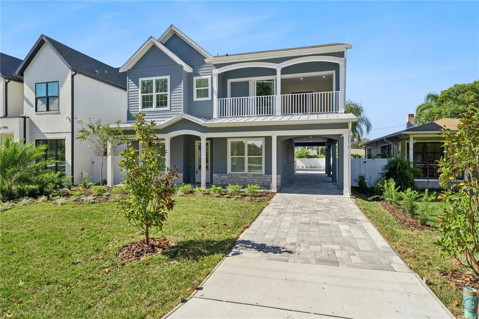 A driveway-side view shows the home's front porch, balcony, and covered side passage.