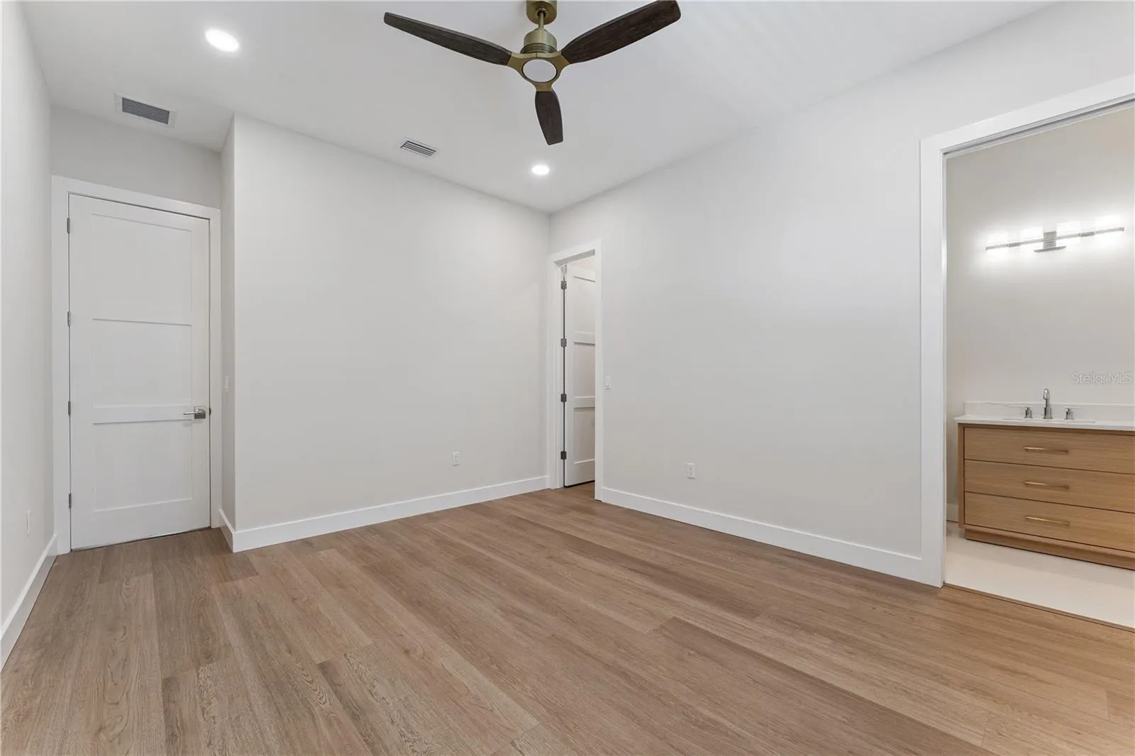 This bedroom includes a shuttered window, ceiling fan, and a view into the built-in closet.