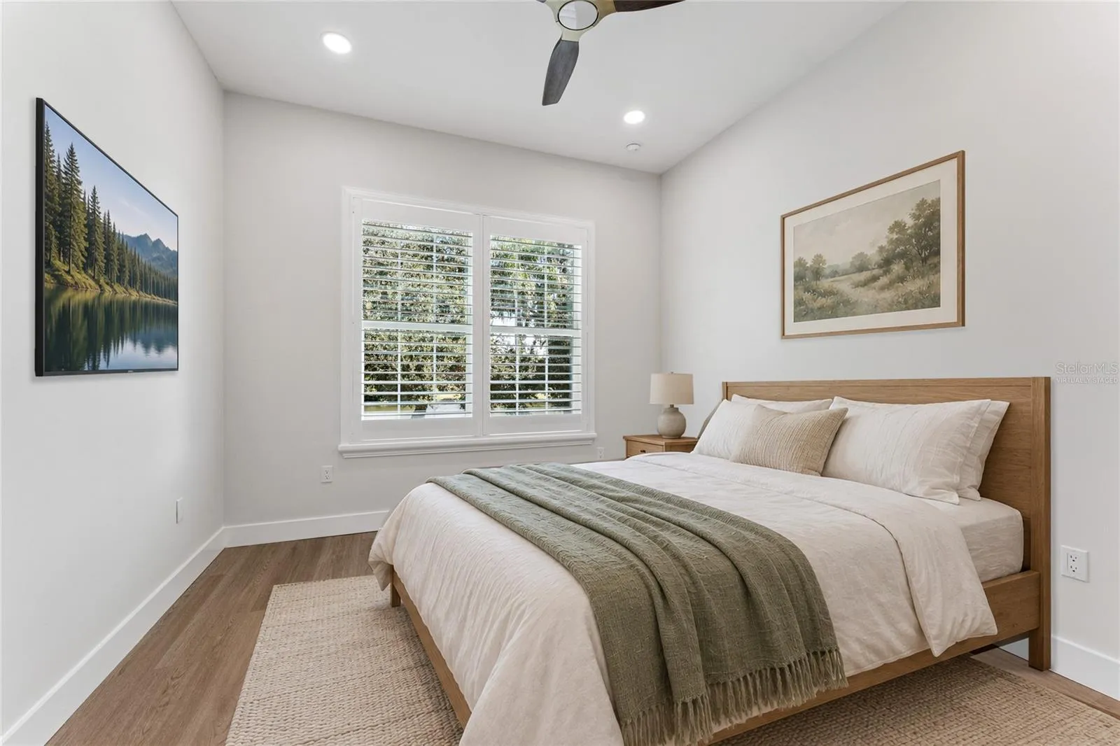 Virtually Staged - A shuttered window, ceiling fan, and light walls create a bright bedroom setting.