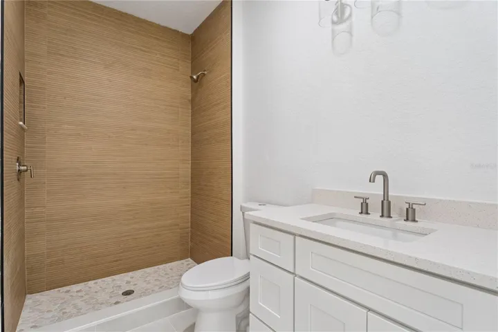 This bathroom features a white vanity and a walk-in shower with wood-look wall tile.
