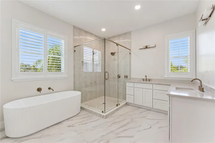 A freestanding tub, glass-enclosed shower, and two sinks define this spacious bathroom.