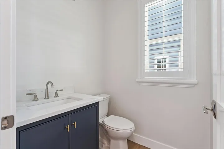 A navy vanity, light countertop, and shuttered window give this powder room a crisp finish.
