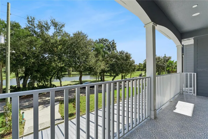 The covered front balcony offers an elevated outlook toward the golf course and surrounding trees.