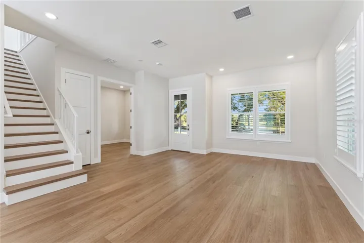 The front room offers natural light, recessed lighting, and a view of the staircase.
