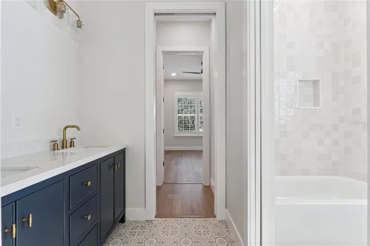A navy double vanity pairs with patterned flooring and a tub-and-shower combination.