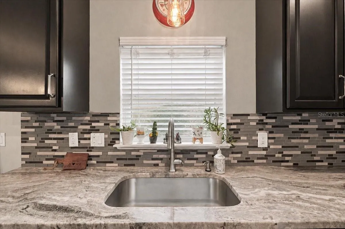 Mable countertops with view to the backyard &amp; deep stainless steel sink.