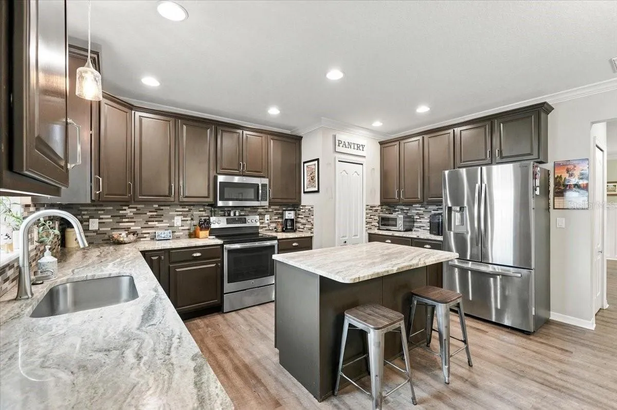 Kitchen with stainless steel appliances, breakfast bar, marble countertops