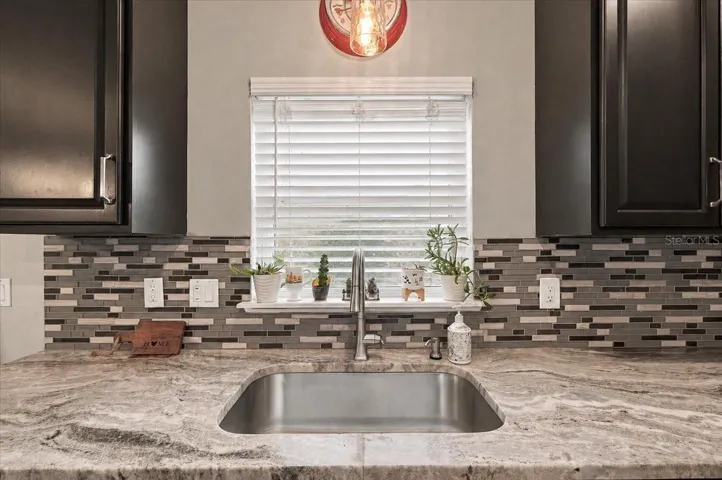 Mable countertops with view to the backyard &amp; deep stainless steel sink.