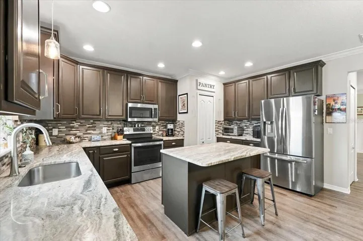 Kitchen with stainless steel appliances, breakfast bar, marble countertops