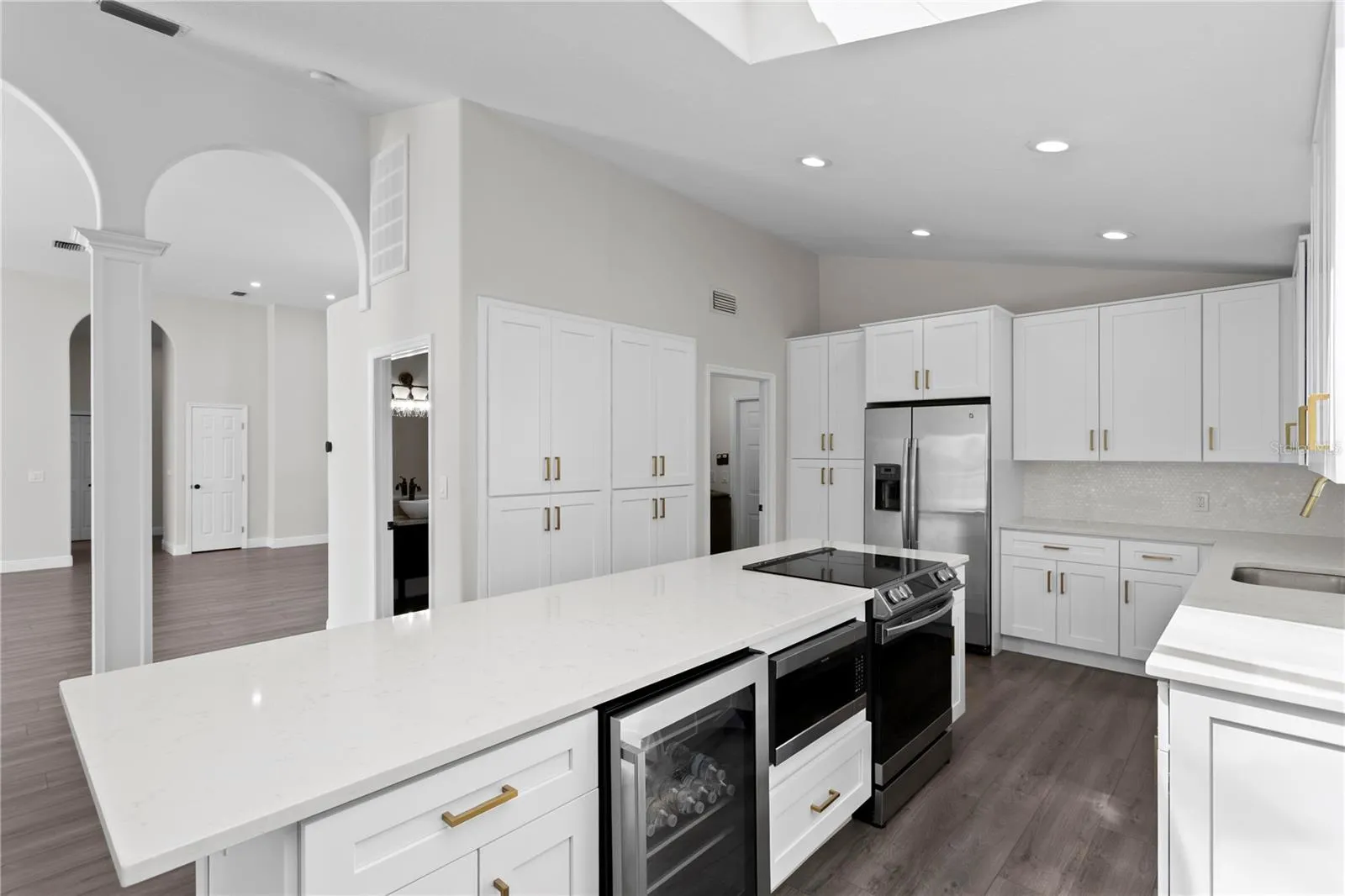 Well-appointed kitchen island featuring a wine refrigerator, microwave, range, additional cabinet storage and breakfast bar seating.