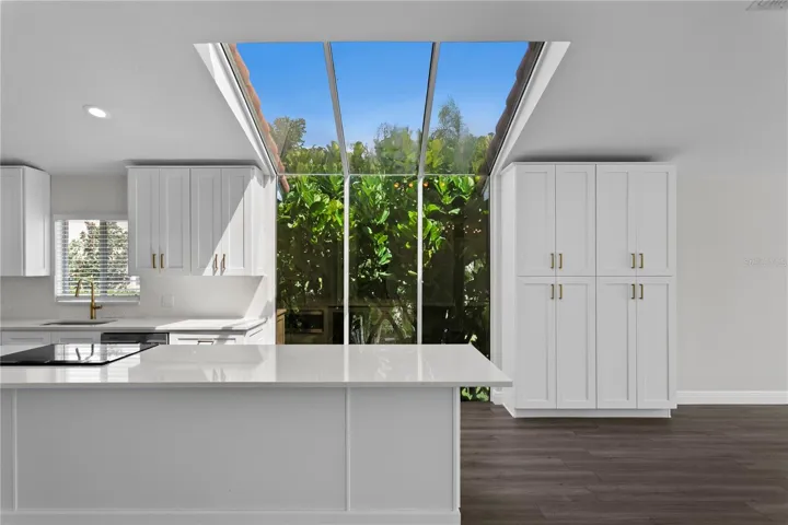 Floor-to-ceiling windows fill the gorgeous kitchen with natural light, complemented by abundant cabinet storage.