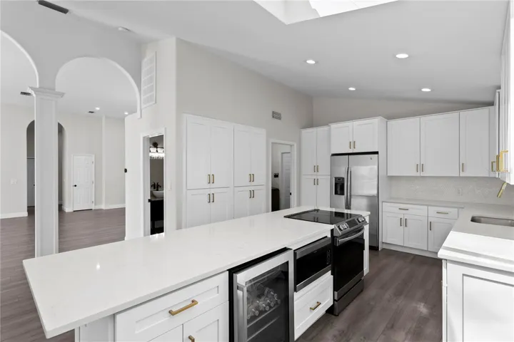 Well-appointed kitchen island featuring a wine refrigerator, microwave, range, additional cabinet storage and breakfast bar seating.