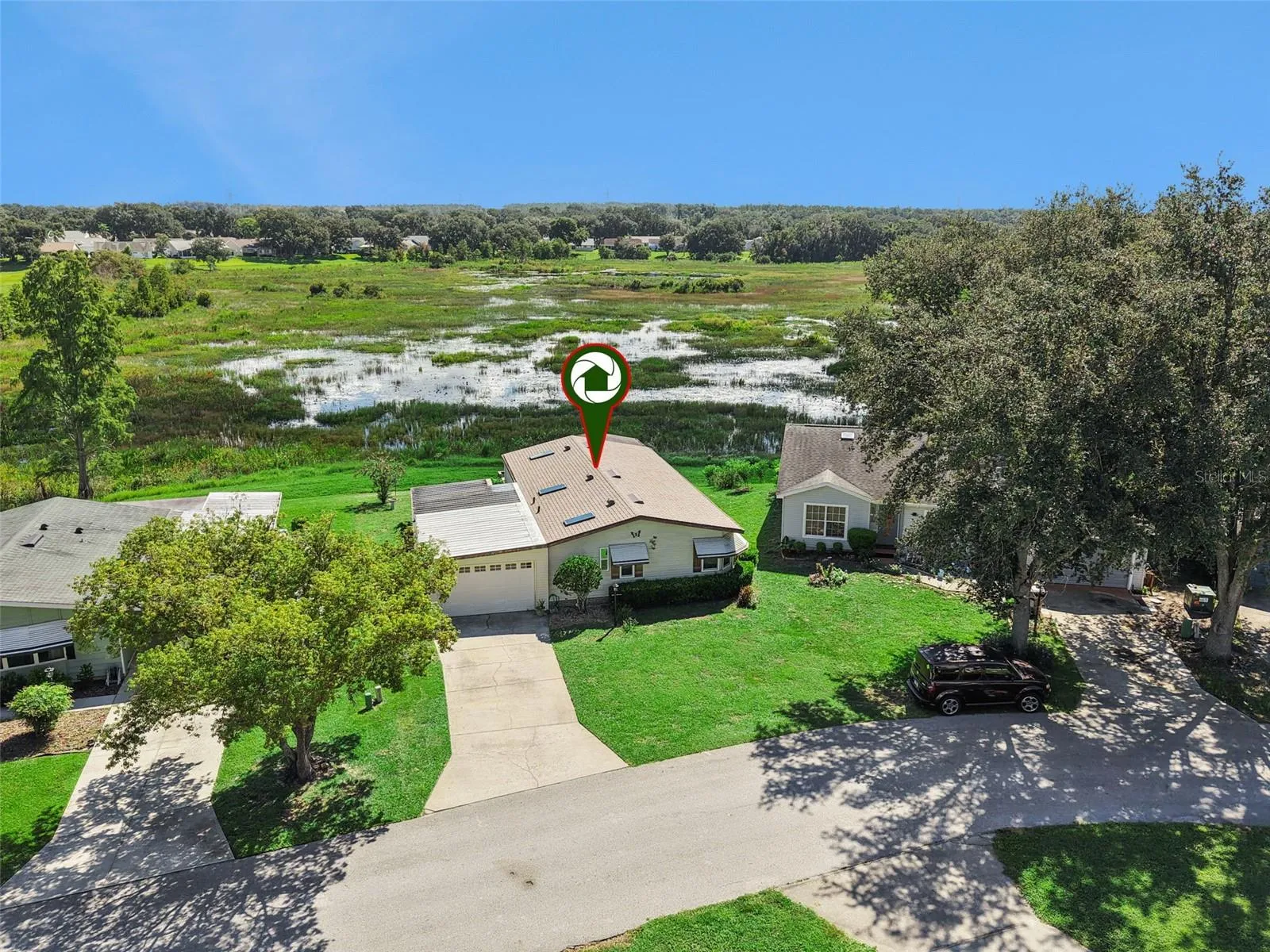 Aerial view with the home marked, backing to the open marsh