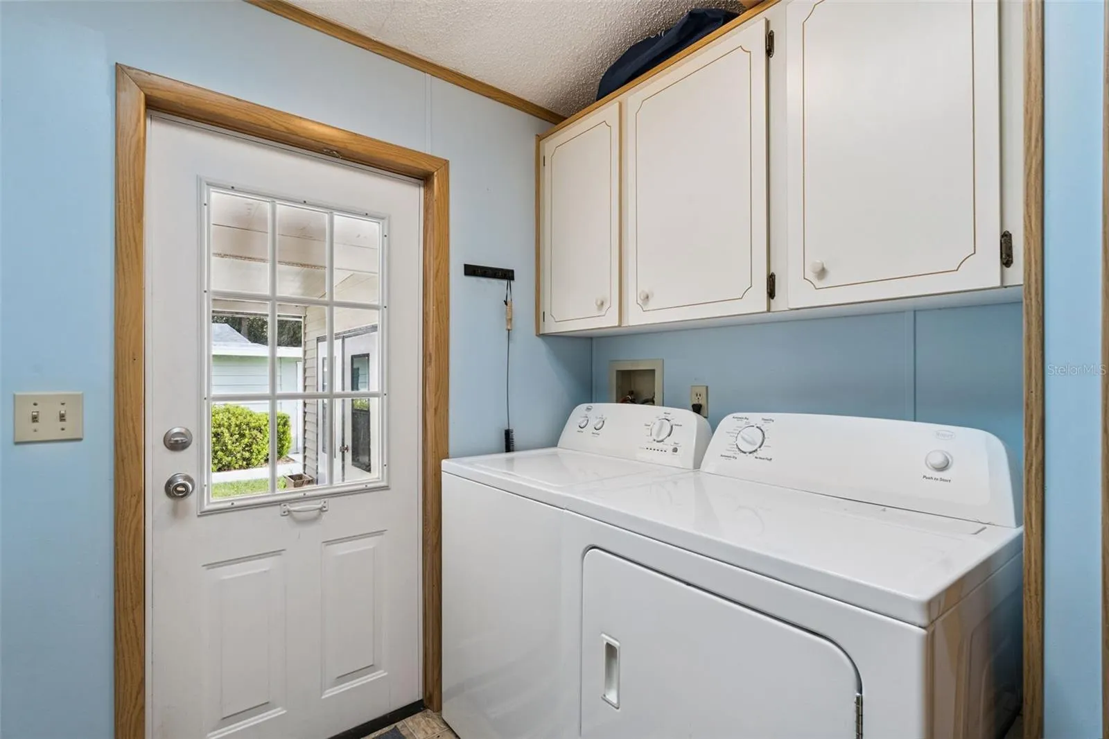 Laundry room with washer, dryer, storage cabinets and door to the front porch