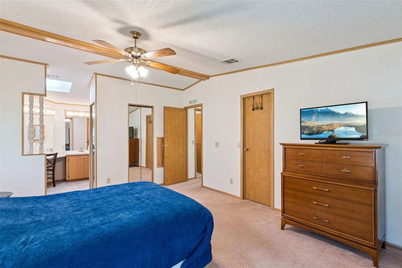 Primary bedroom with ceiling fan and an open view to the en-suite vanity