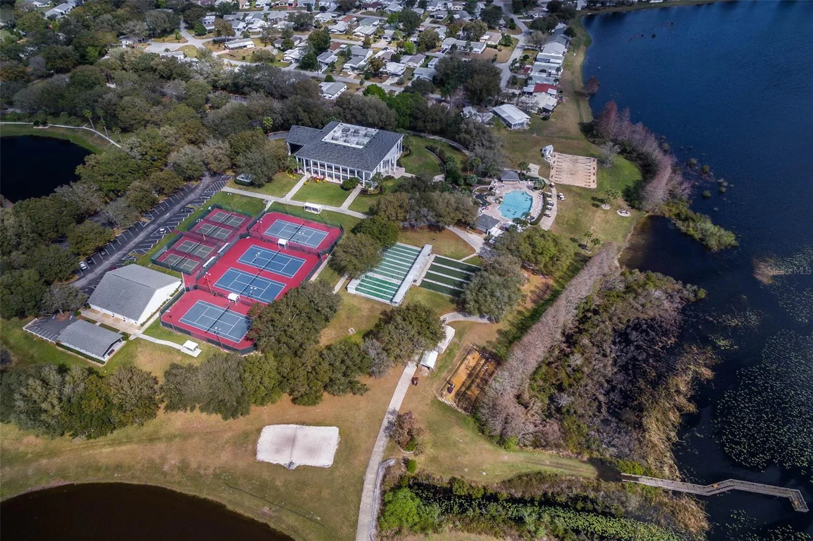 Community amenity: aerial view of the clubhouse, courts and pool along the lake