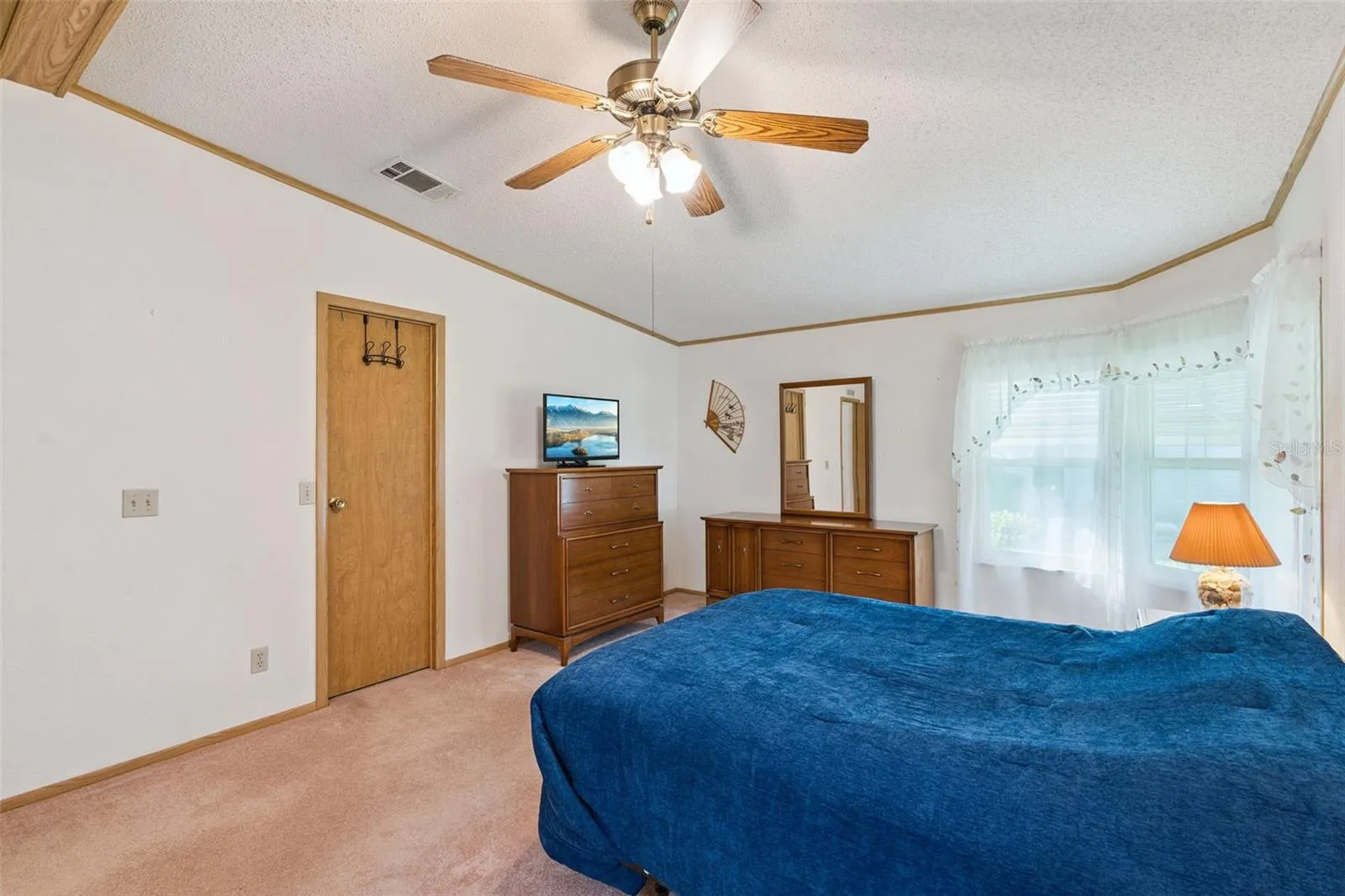 Primary bedroom with corner windows and ceiling fan