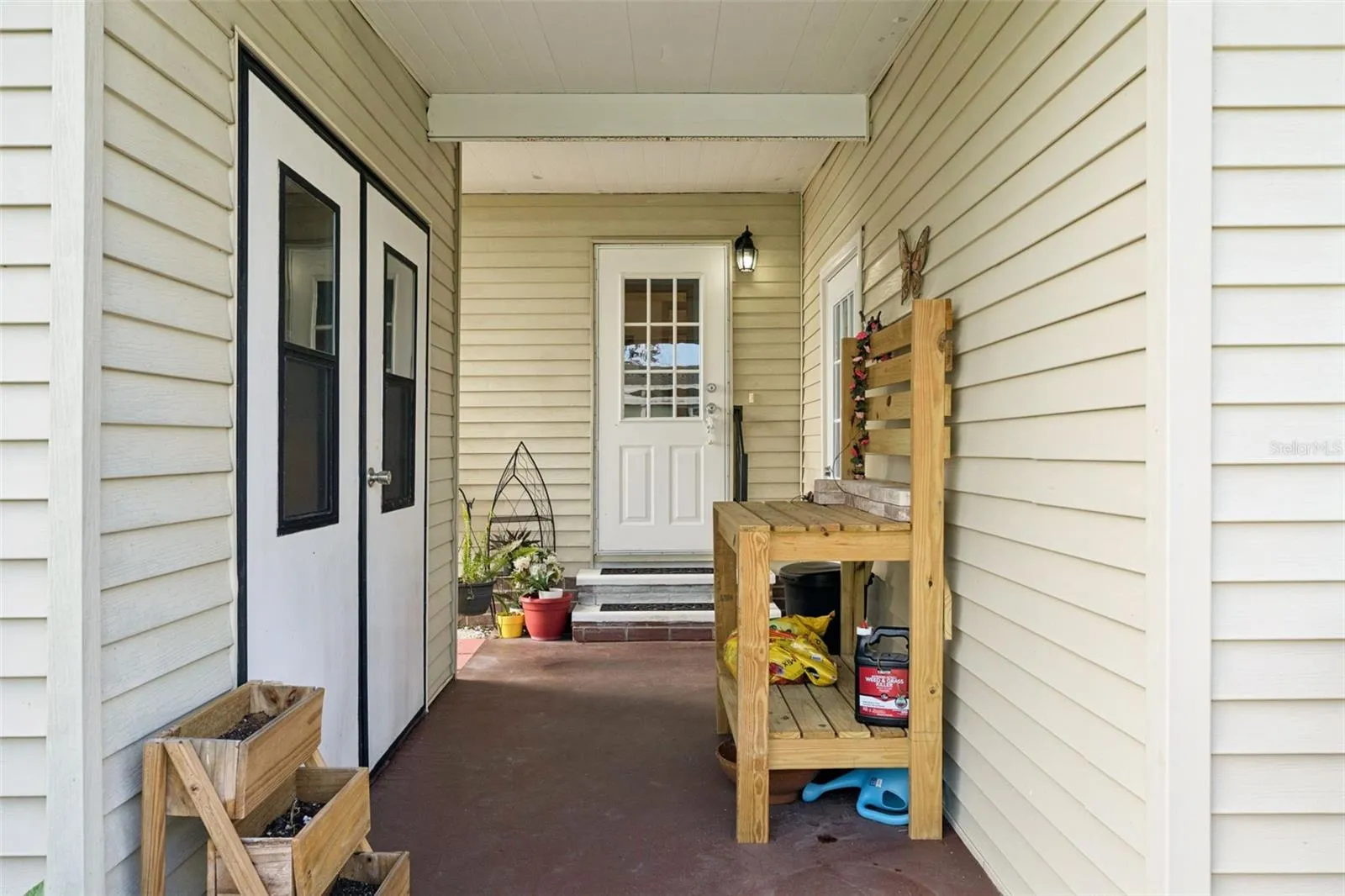 Covered front porch at the main entry, with double doors to the exterior storage room