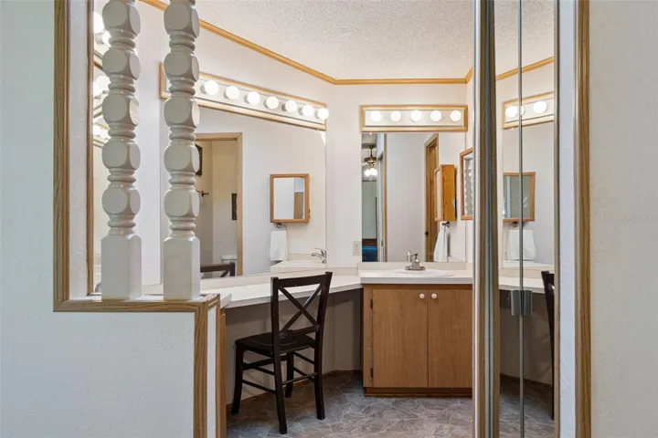 Primary bathroom vanity area with built-in makeup desk and walk-in shower