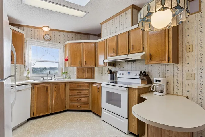Kitchen with range, dishwasher, ample cabinets and curved breakfast bar