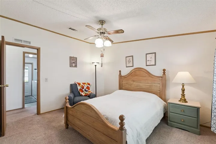 Guest bedroom with ceiling fan and doorway to the hall