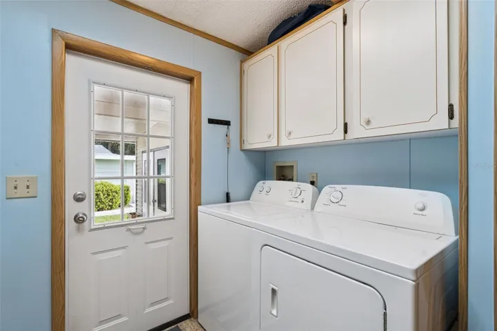 Laundry room with washer, dryer, storage cabinets and door to the front porch