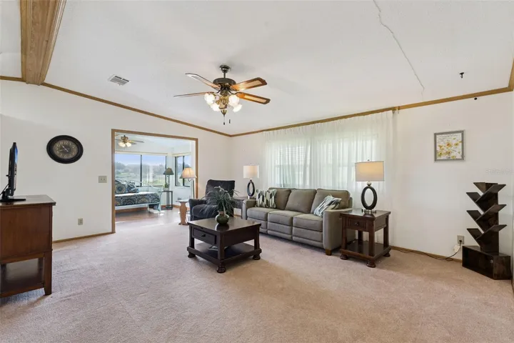 Living room with vaulted ceiling, ceiling fan and an opening into the sunroom