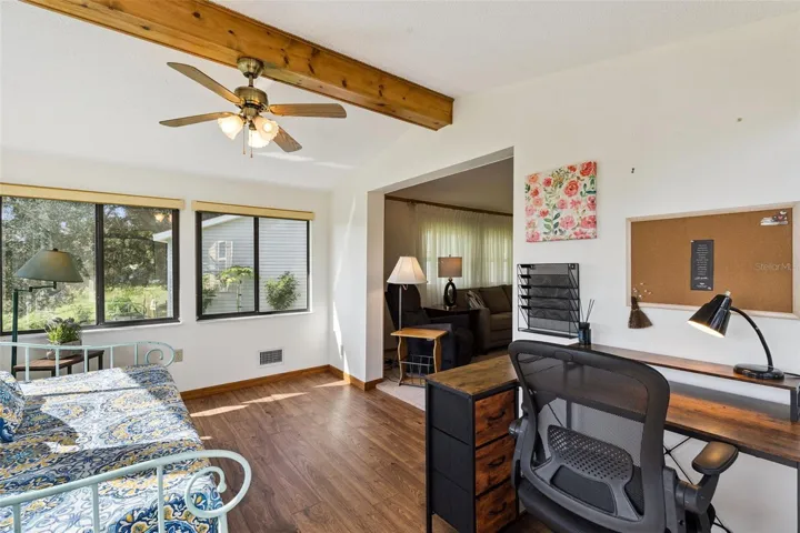 Sunroom with windows on three sides and a beamed vaulted ceiling
