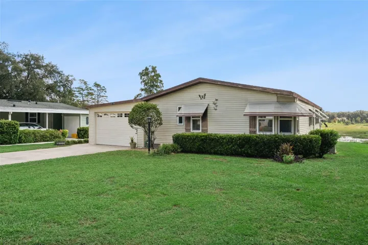 Front and side exterior with manicured hedges and a spacious lawn