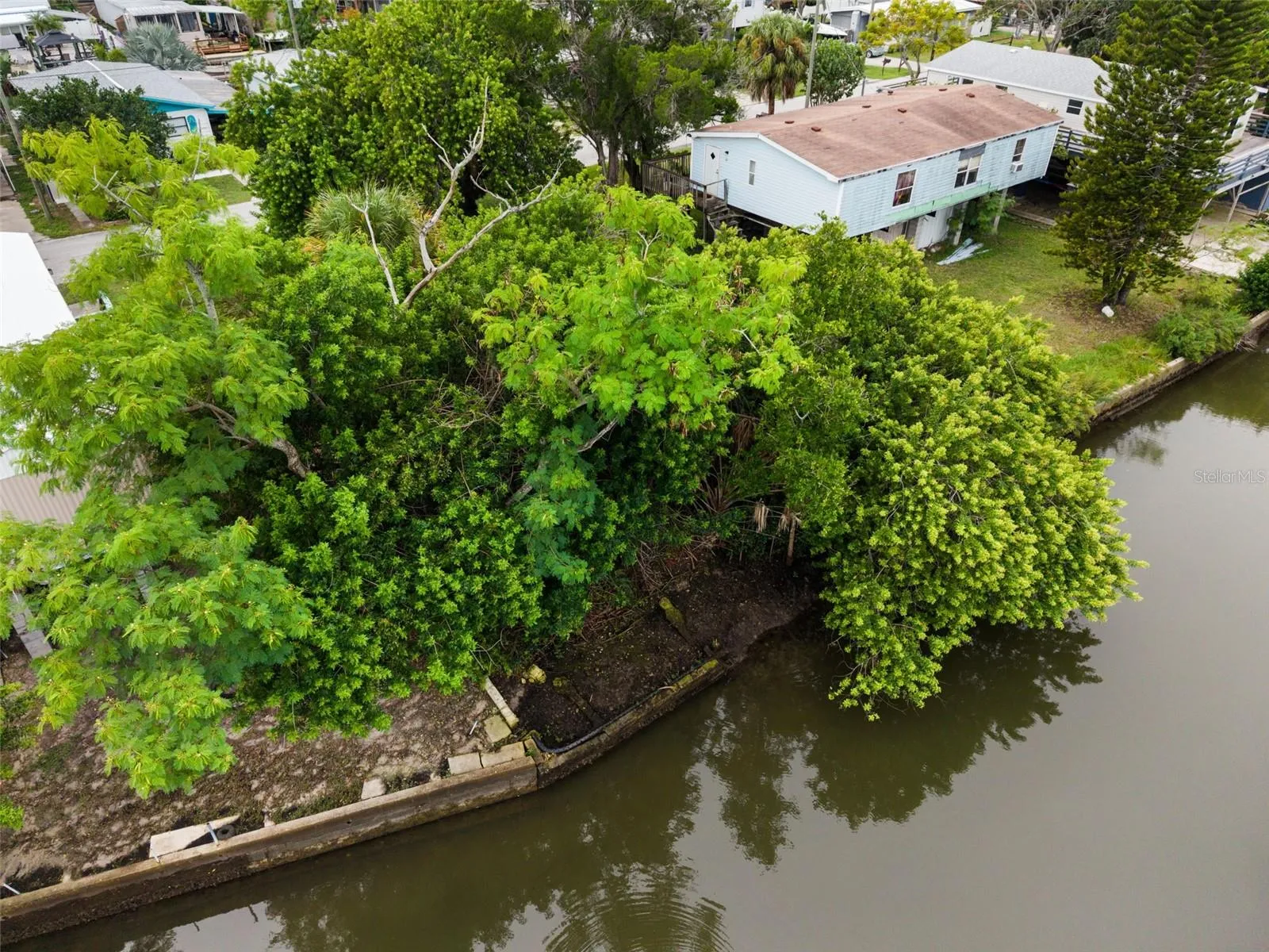 Closer aerial view of the canal frontage, seawall, and natural surroundings.