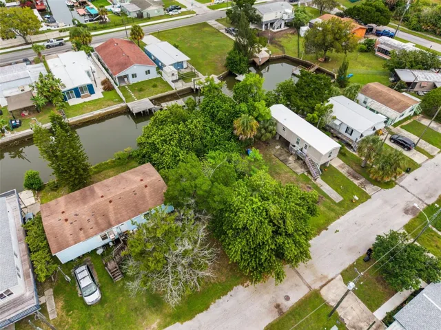 Aerial neighborhood view showcasing the canal, nearby waterfront homes, and future building opportunity.