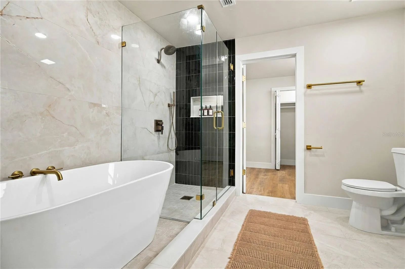 Primary bath with soaking tub, a walk in shower, and leading into walk in closet