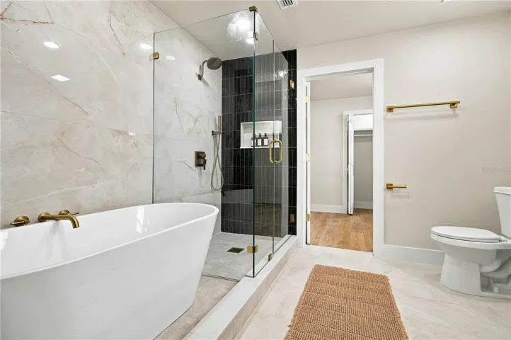 Primary bath with soaking tub, a walk in shower, and leading into walk in closet