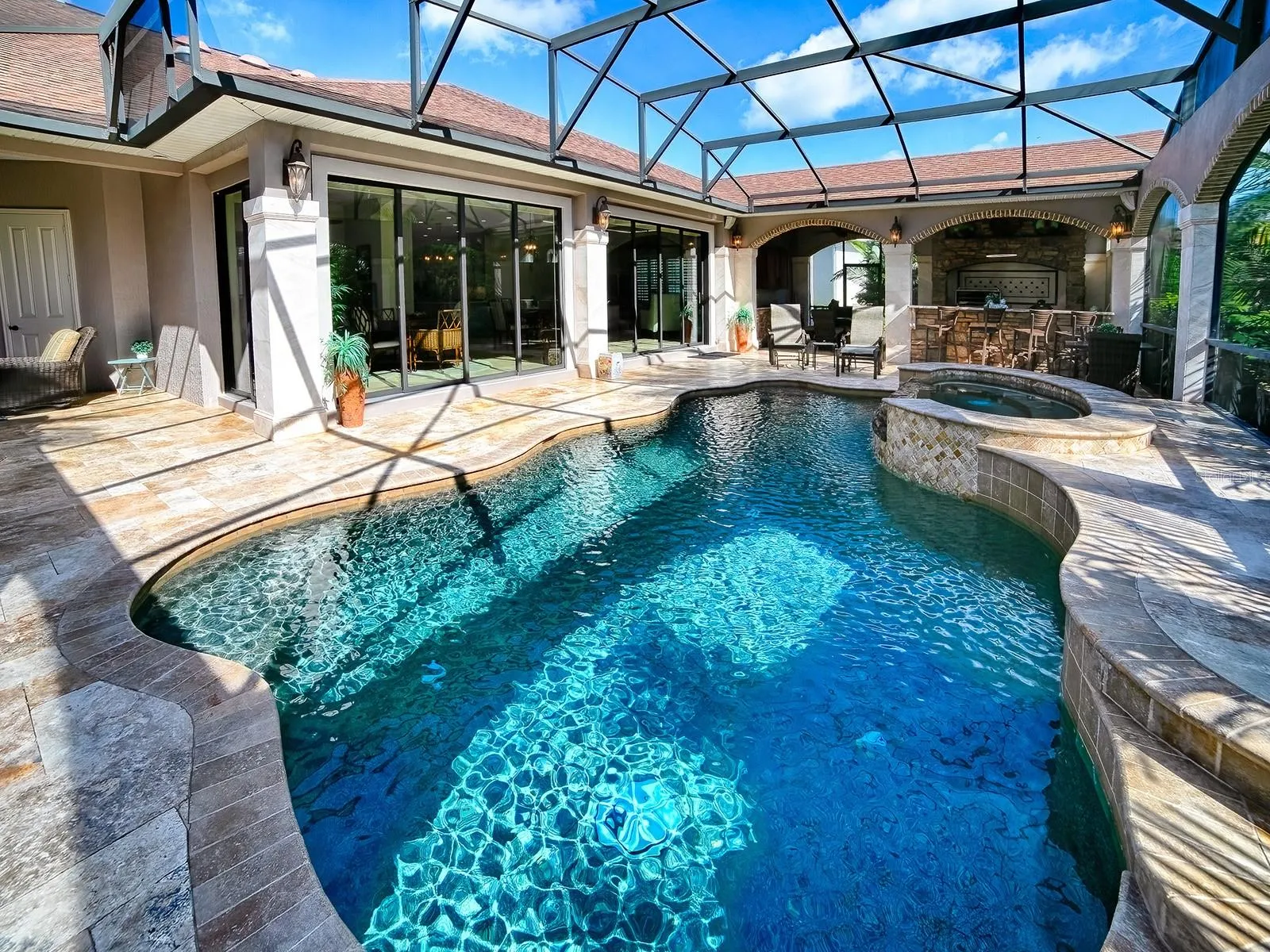 AN AMAZING SALT WATER HEATED POOL AND SPA WITH TRAVERTINE DECKING AND A SUMMER KITCHEN.