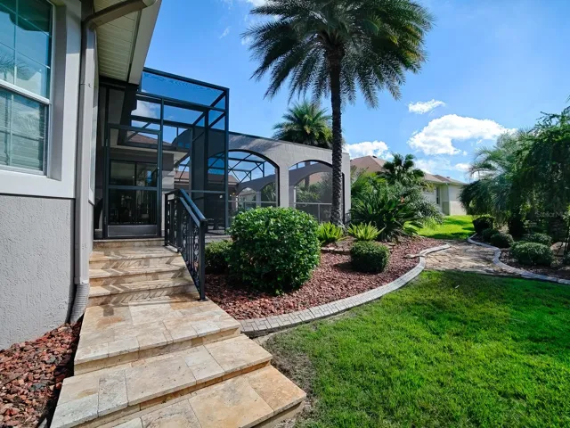 THIS IS THE RIGHT SIDE OF THE HOME WITH TRAVERTINE STEPS LEADING TO THE POOL AREA.