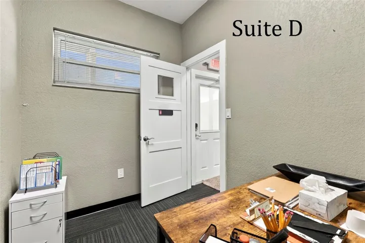 Suite D has a high window and is located near the hall restroom and Covered Patio Break Common Area