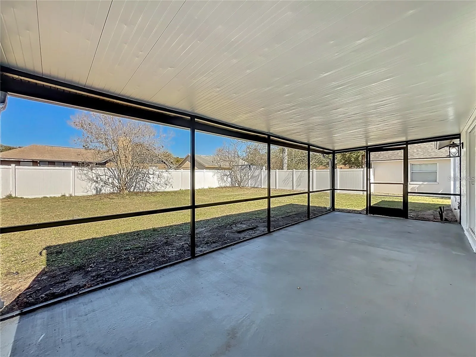 View of screened in patio and fenced backyard.