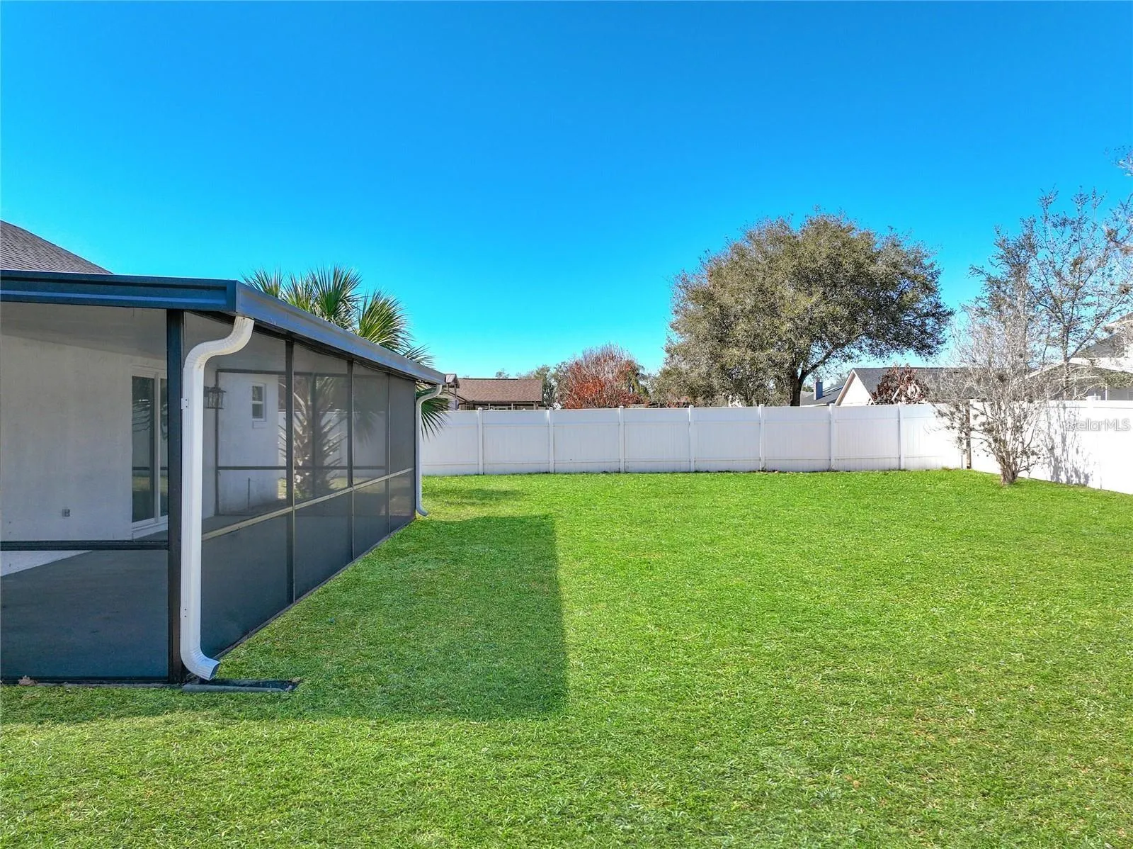 View of vinyl fencing, mature landscaping.