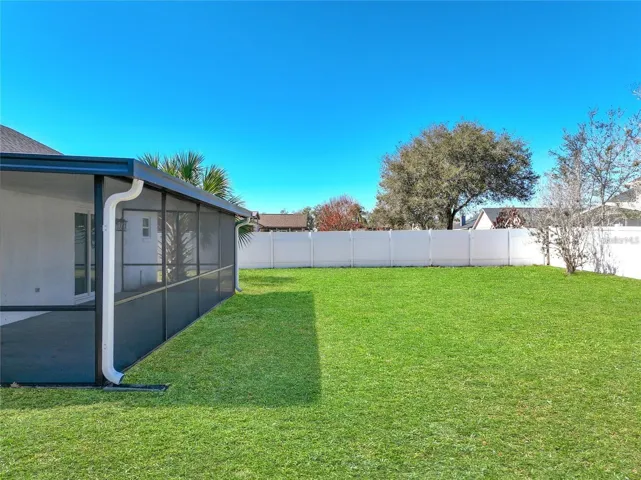 View of vinyl fencing, mature landscaping.